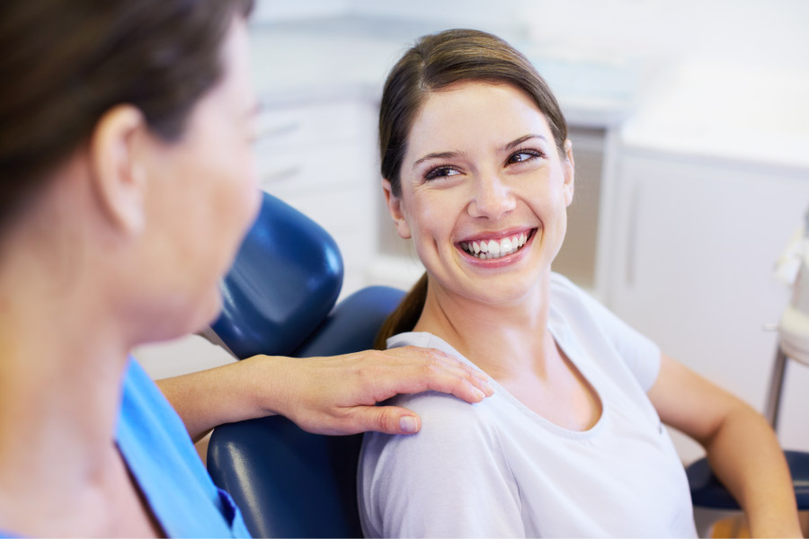 Brunette woman smiles while sitting in a chair at the dentist in Chandler, AZ