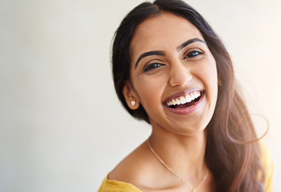 Brunette brown woman smiles confidently after professional teeth whitening in Chandler, AZ